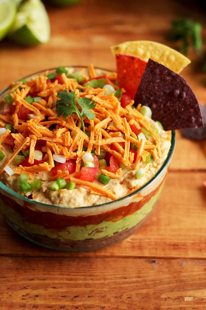 The BEST Vegan 7 Layer Dip - Homemade low-fat refried beans, creamy guacamole, zesty tomato salsa, hummus (no need for sour cream!), vegan cheese, and fresh chopped tomato & green onion! This easy dip is free of gluten and soy, and perfect for a holiday appetizer! #vegan #glutenfree #christmas - ilovevegan.com