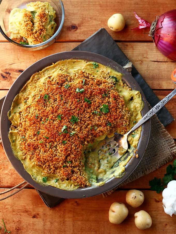 Cheesy Vegan Potato & Broccoli Casserole with a serving spoon and one portion already served.