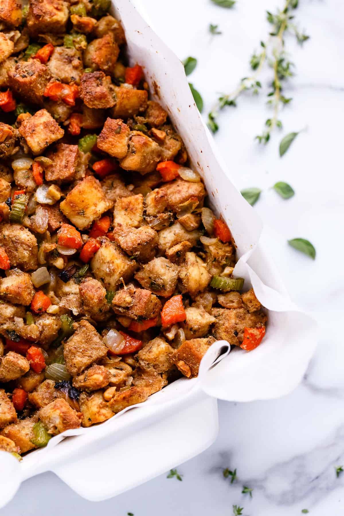 Vegan vegetable stuffing in a white casserole dish.