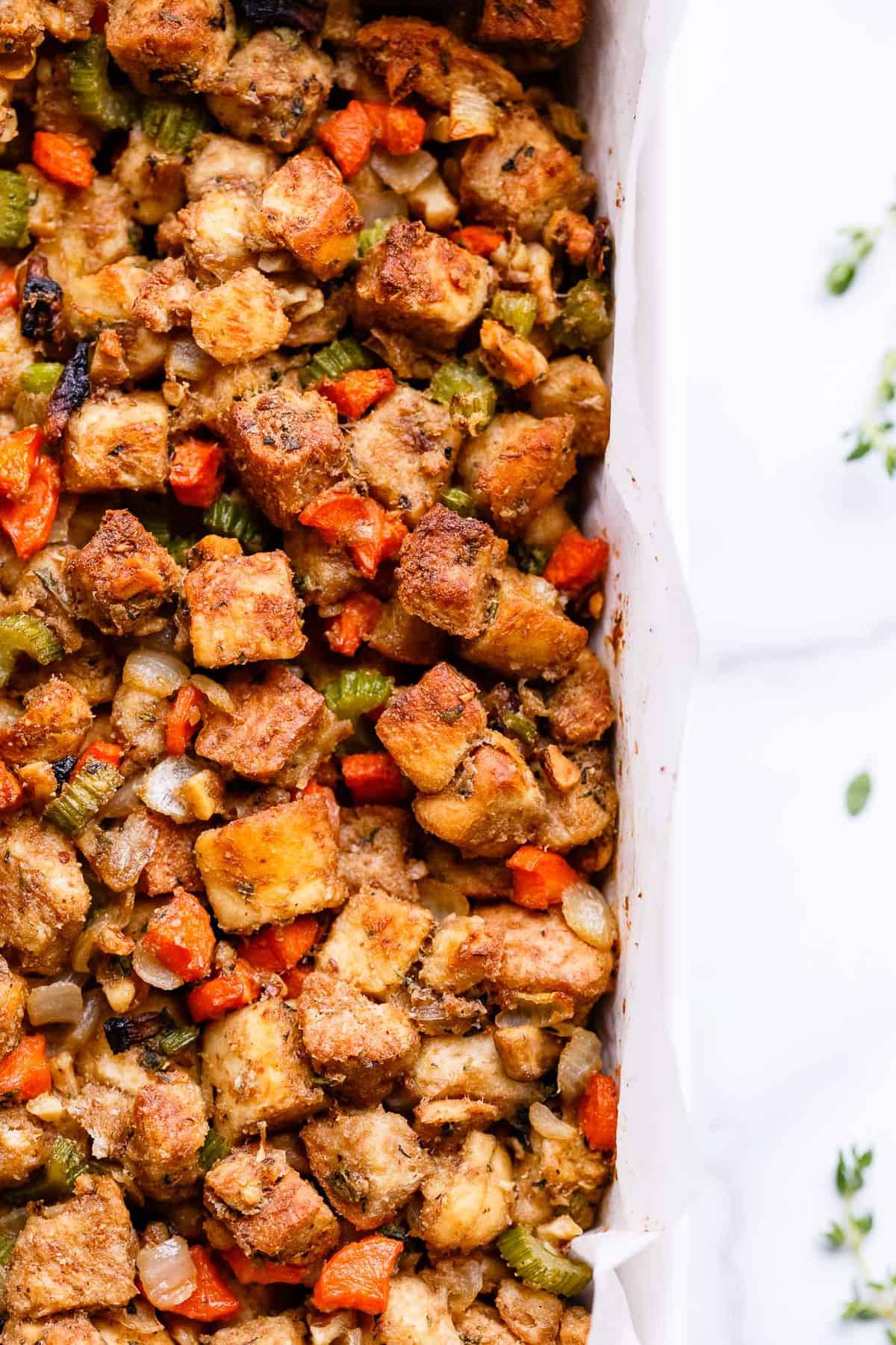 Vegan vegetable stuffing in a white casserole dish.