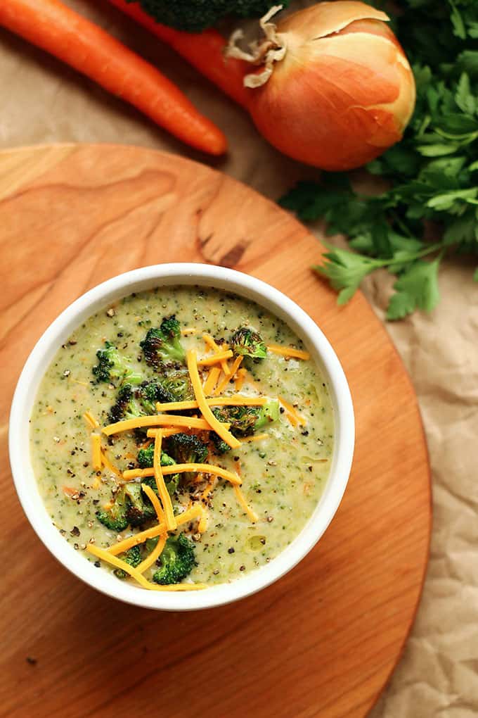 A bowl of Creamy Vegan Broccoli Soup topped with roasted broccoli and vegan cheese shreds.