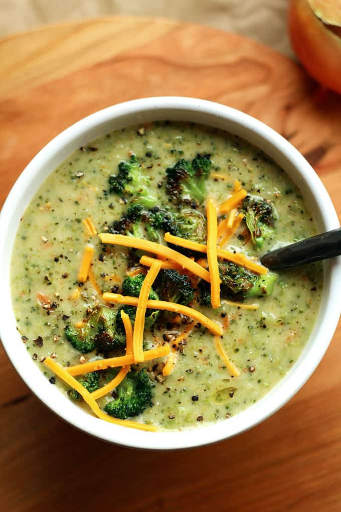 Closeup of a bowl of Creamy Vegan Broccoli Soup topped with roasted broccoli and vegan cheese shreds.