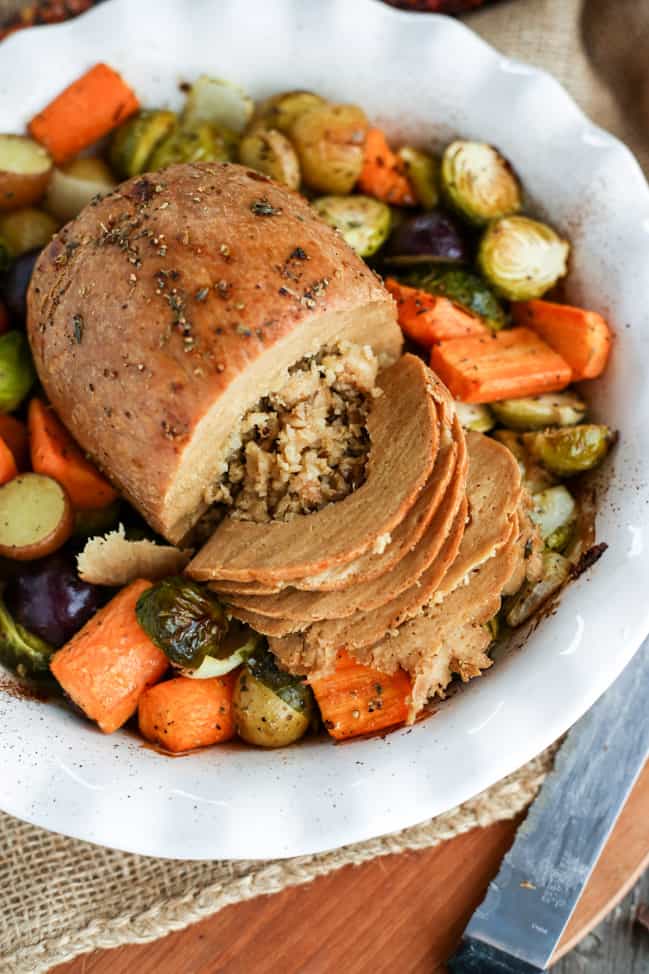 Partially carved Tofurky roast surrounded by roasted vegetables.