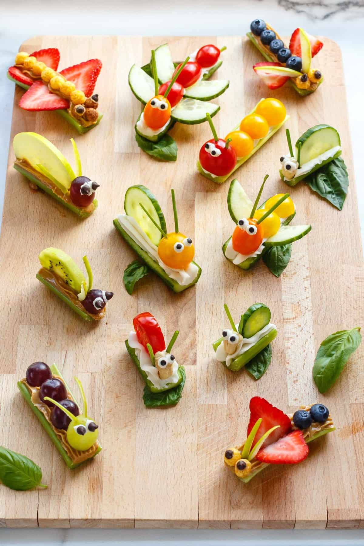 Fruit and vegetable bug snacks arranged on a wood board.