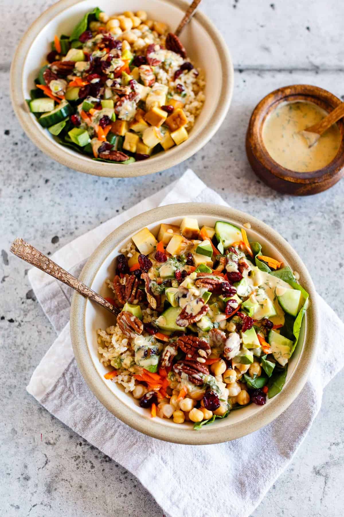 2 Vegan Goddess Bowls with Tahini Dressing on a concrete background.