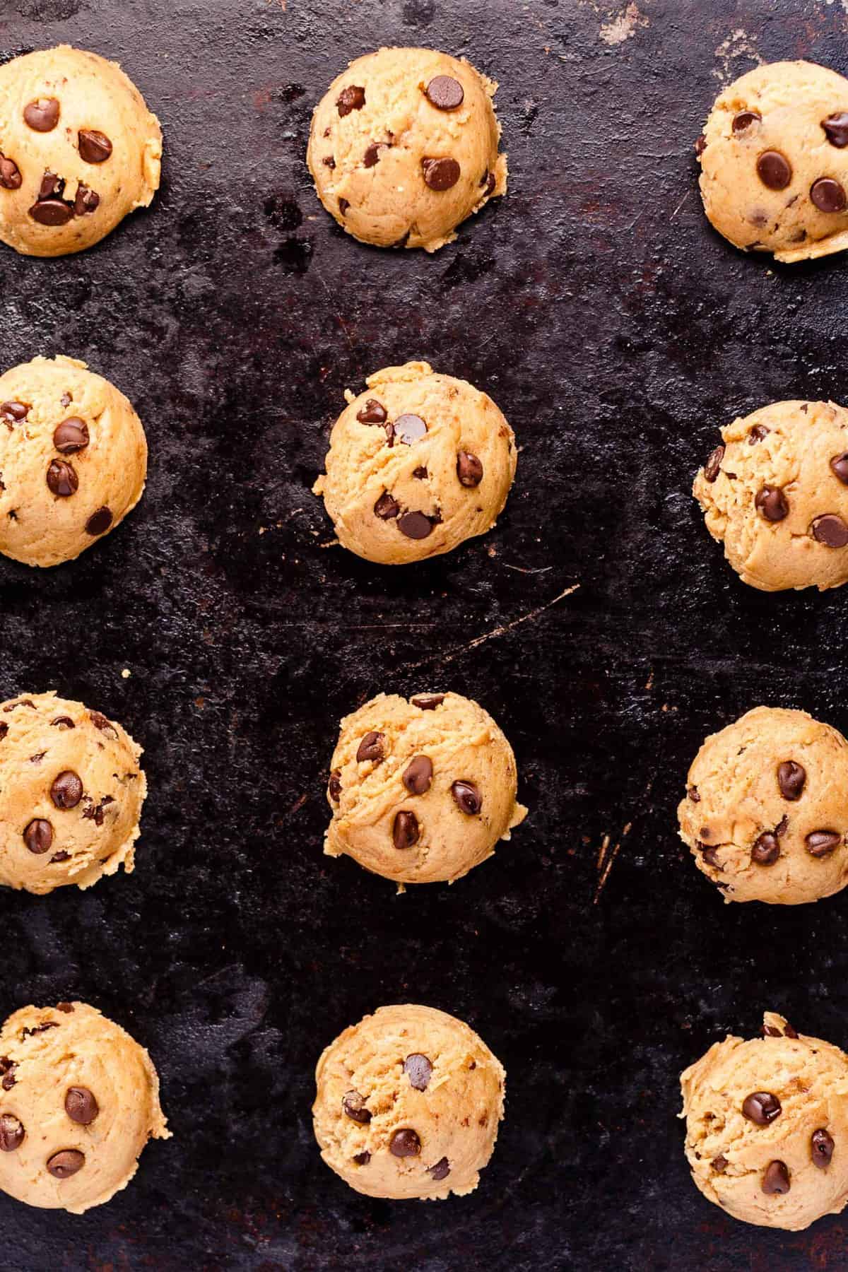Vegan chocolate chip cookie dough portioned out on a baking sheet.