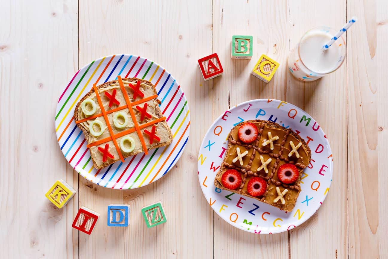 Two pieces of toast decorated as a tic-tac-toe board on colourful patterned plates.