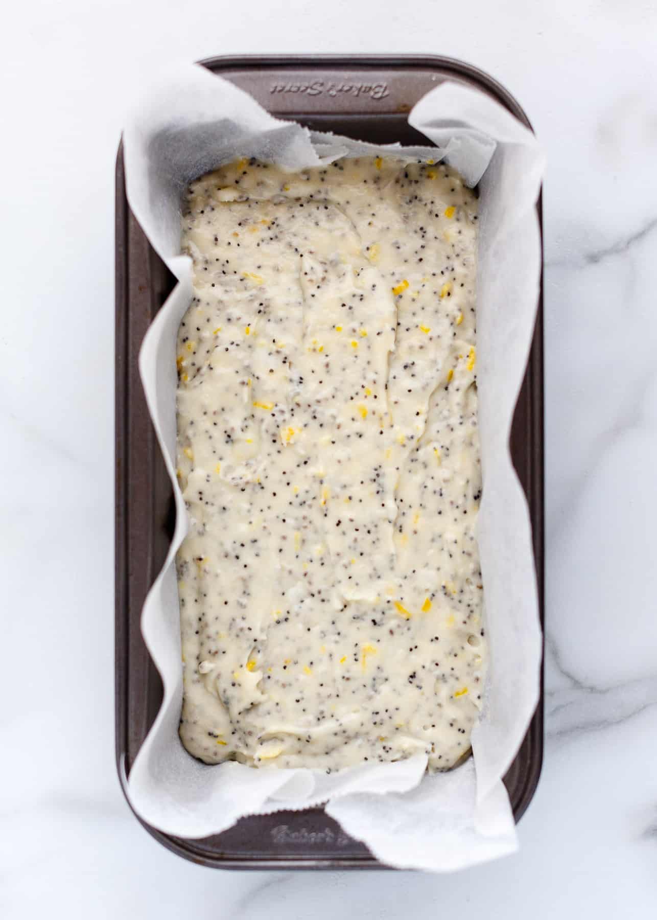Vegan Lemon Poppy Seed Cake batter in a loaf pan lined with parchment paper.