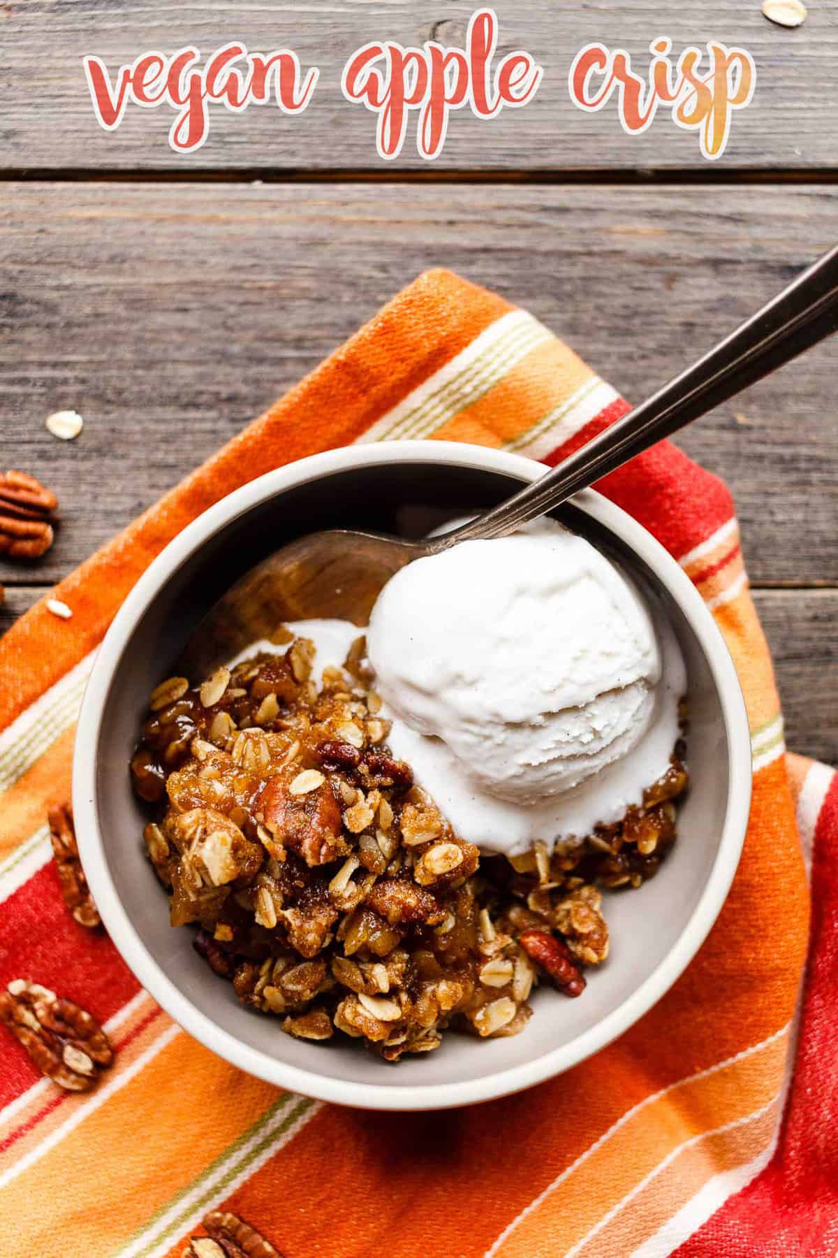 A bowl of vegan apple crisp served with a scoop of dairy-free vanilla ice cream.
