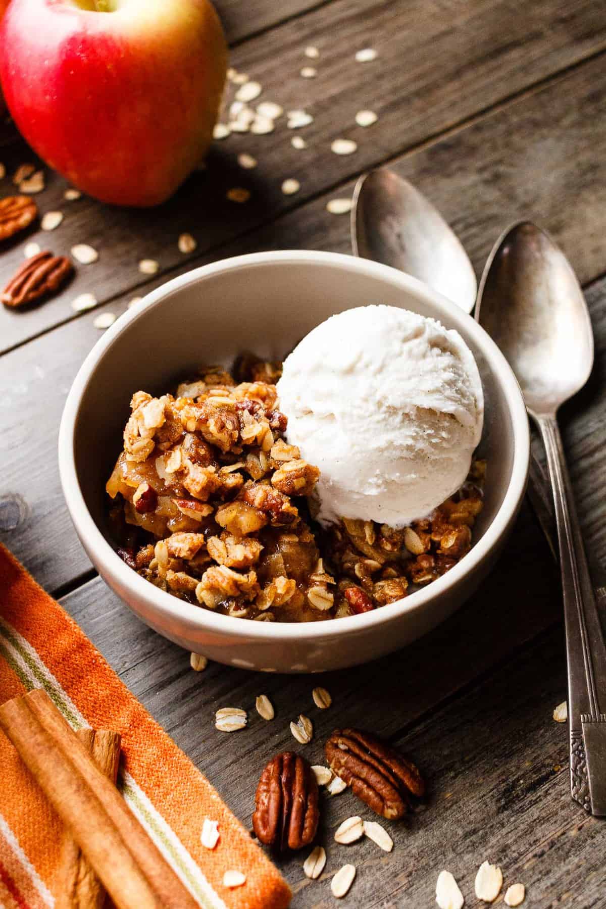 A bowl of vegan apple crisp served with a scoop of dairy-free vanilla ice cream.