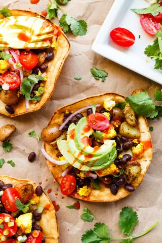 Vegan breakfast tostadas topped with avocado, hot sauce, tomtatoes, and cilantro.
