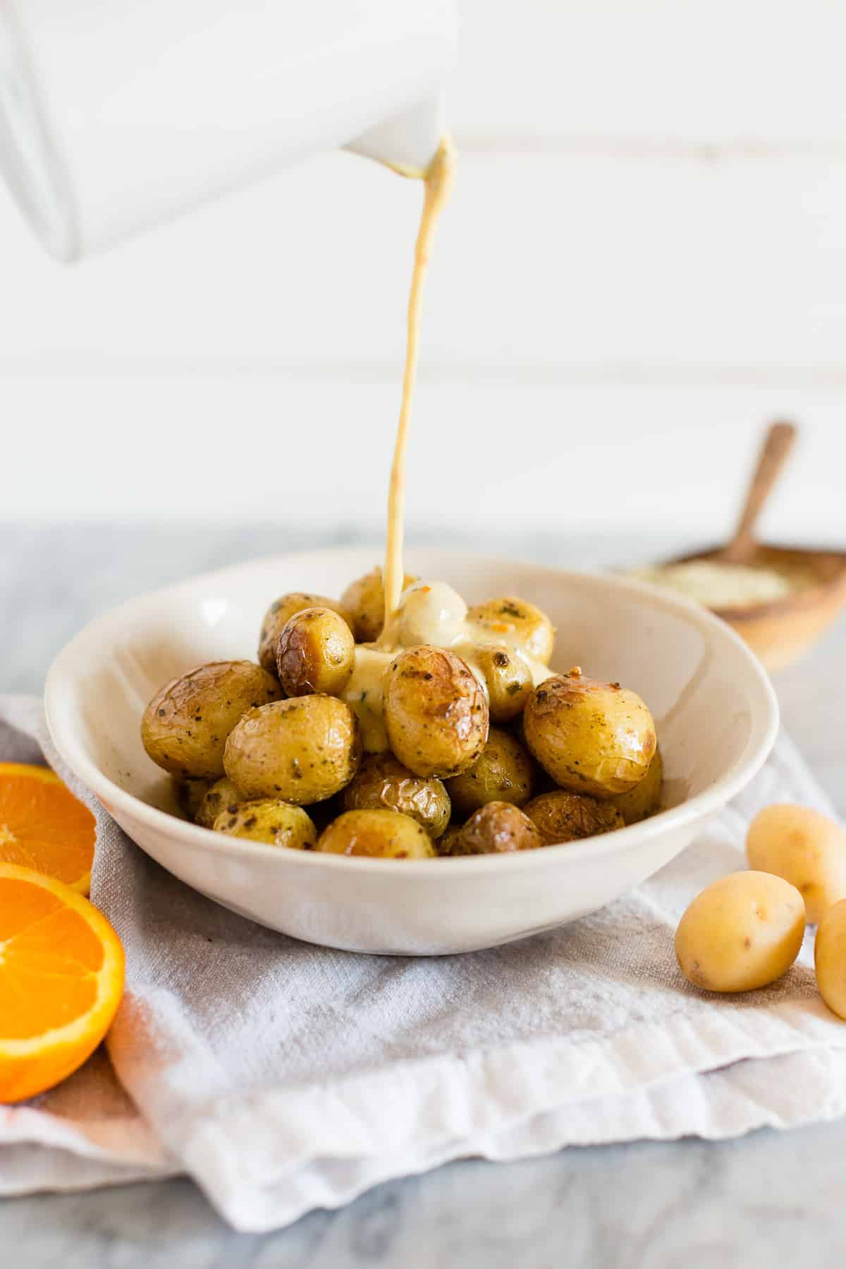 Pouring orange Dijon dressing over Onion & Chive Oven | Grill Ready Little Potatoes.