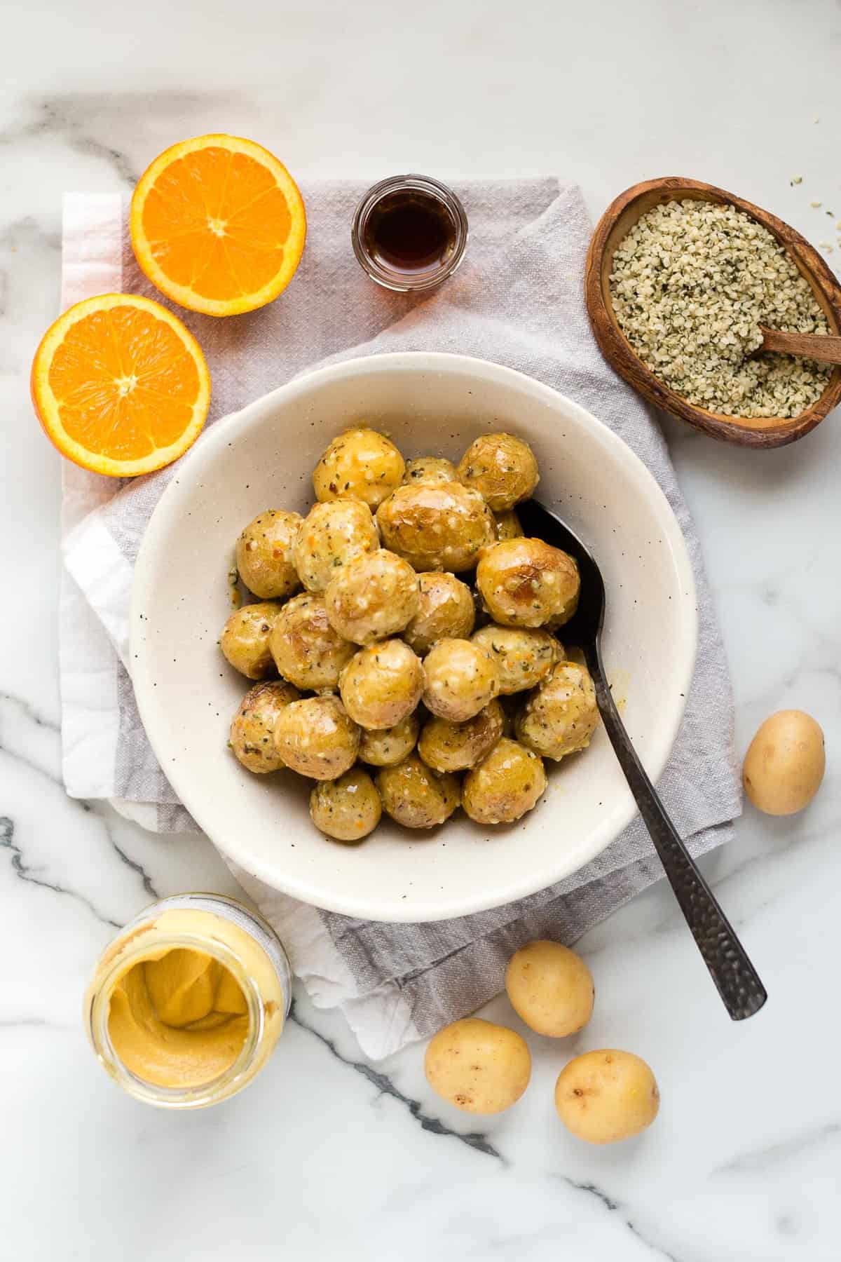 Overhead shot of a bowl of vegan orange dijon little potatoes on a marble counter top.