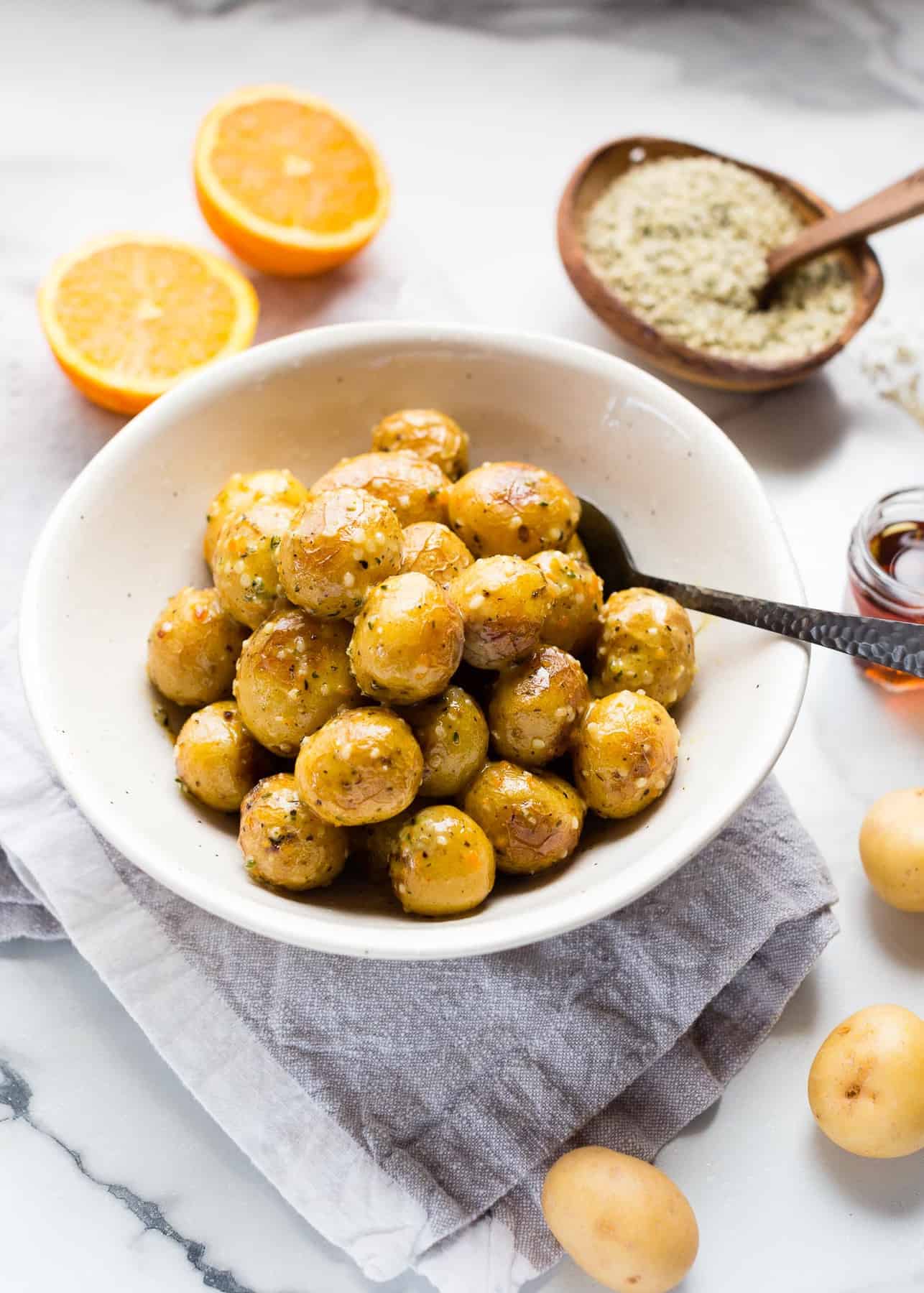 A bowl of vegan orange dijon little potatoes on a marble counter top.