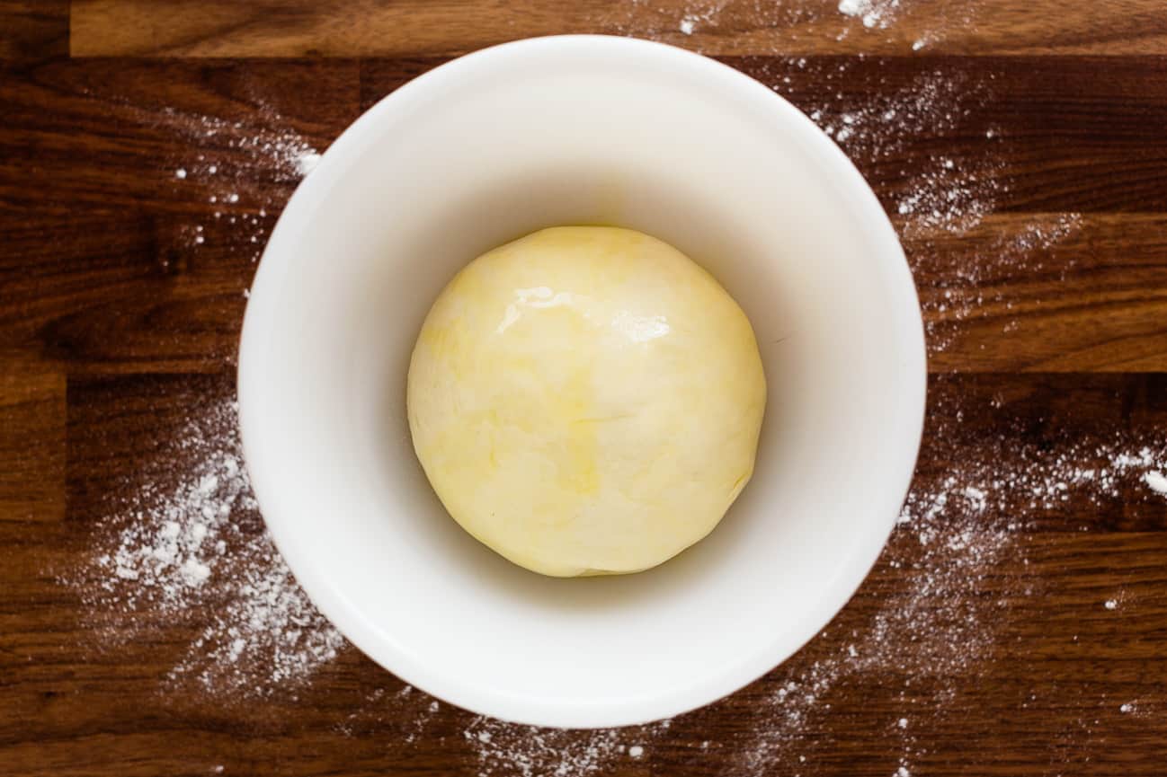 Oiled focaccia dough ball in a bowl, ready to rise.