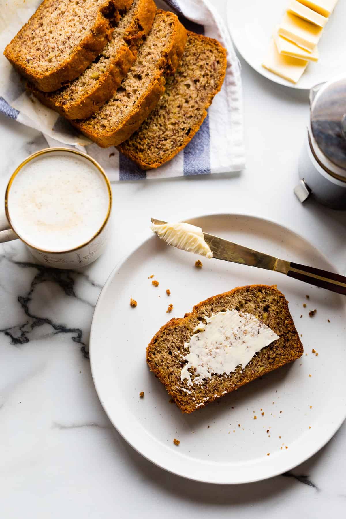 Breakfast scene featuring vegan banana bread and coffee on a marble counter top.