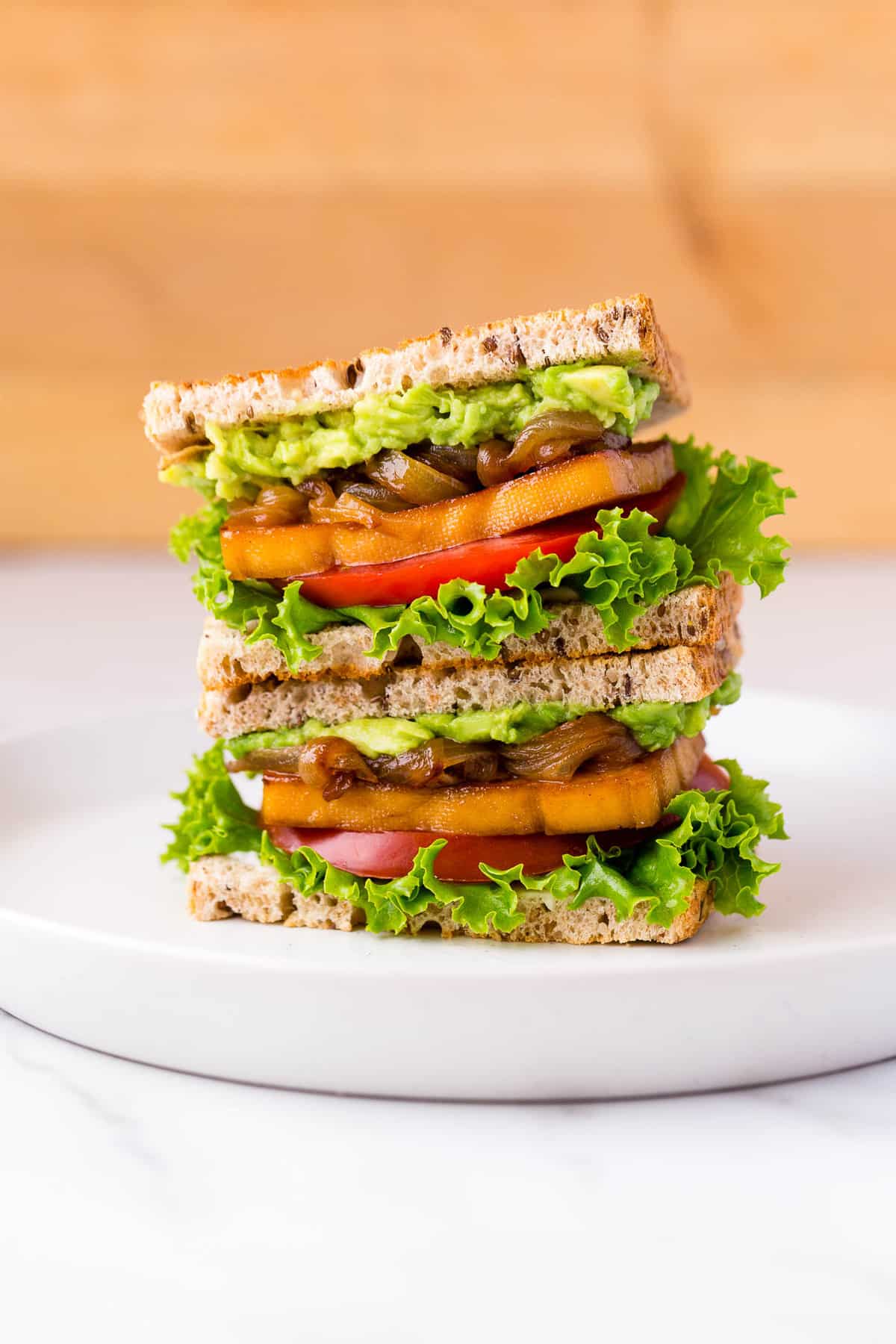 Stacked smoky maple tofu sandwiches on a plate.