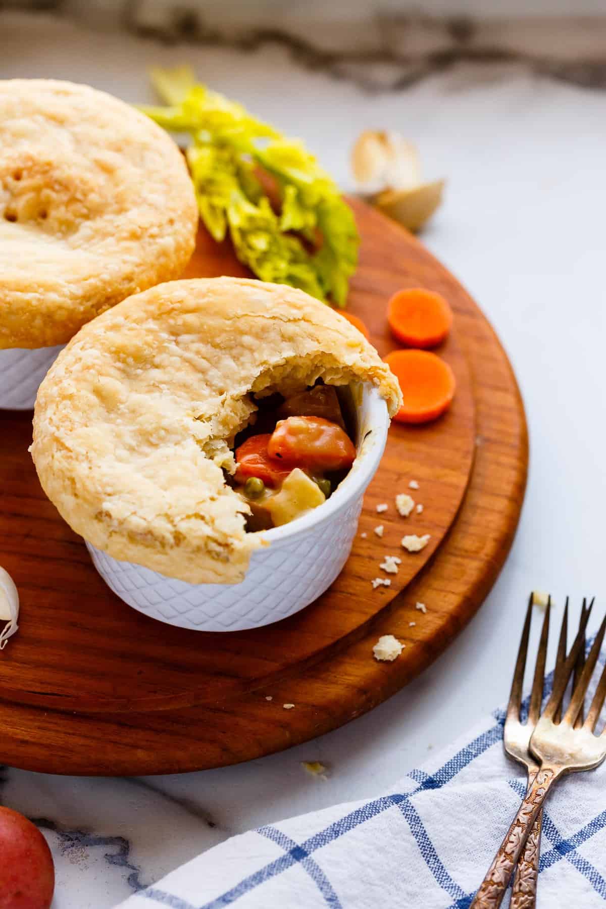 Vegan pot pies topped with flaky pastry crust with filling revealed.