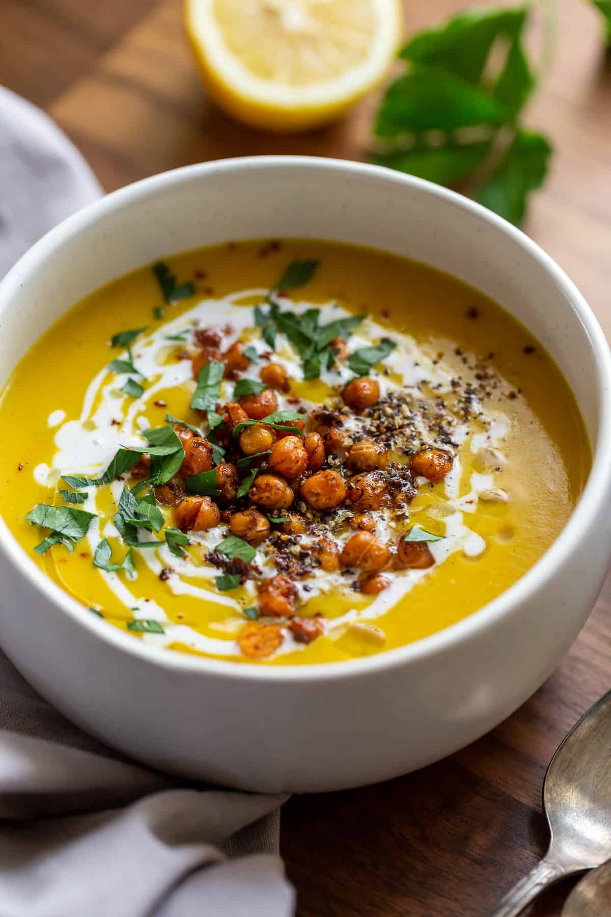 Bowl of chickpea turmeric soup topped with a swirl of coconut cream, crispy spiced chickpeas, and chopped herbs.