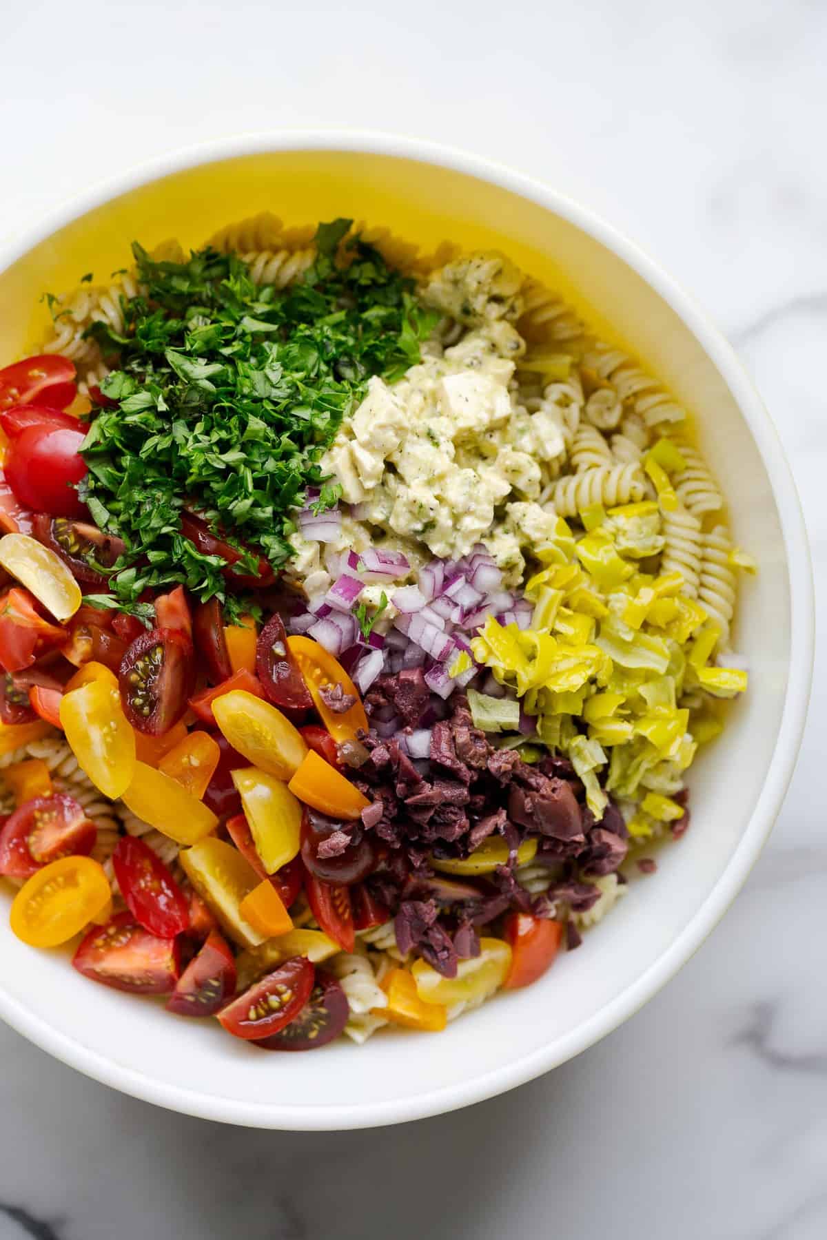 Vegan Italian pasta salad ingredients in a mixing bowl.