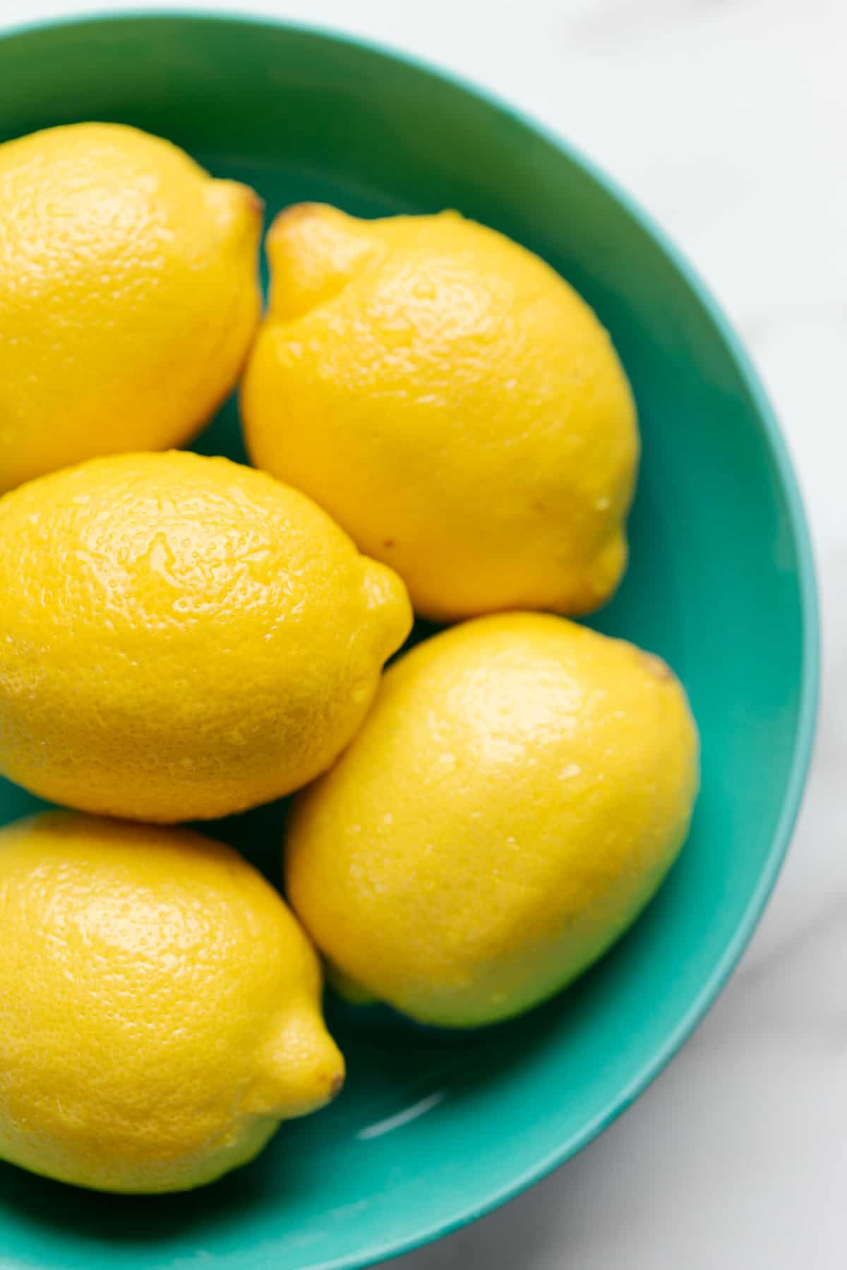 Lemons in a teal bowl.
