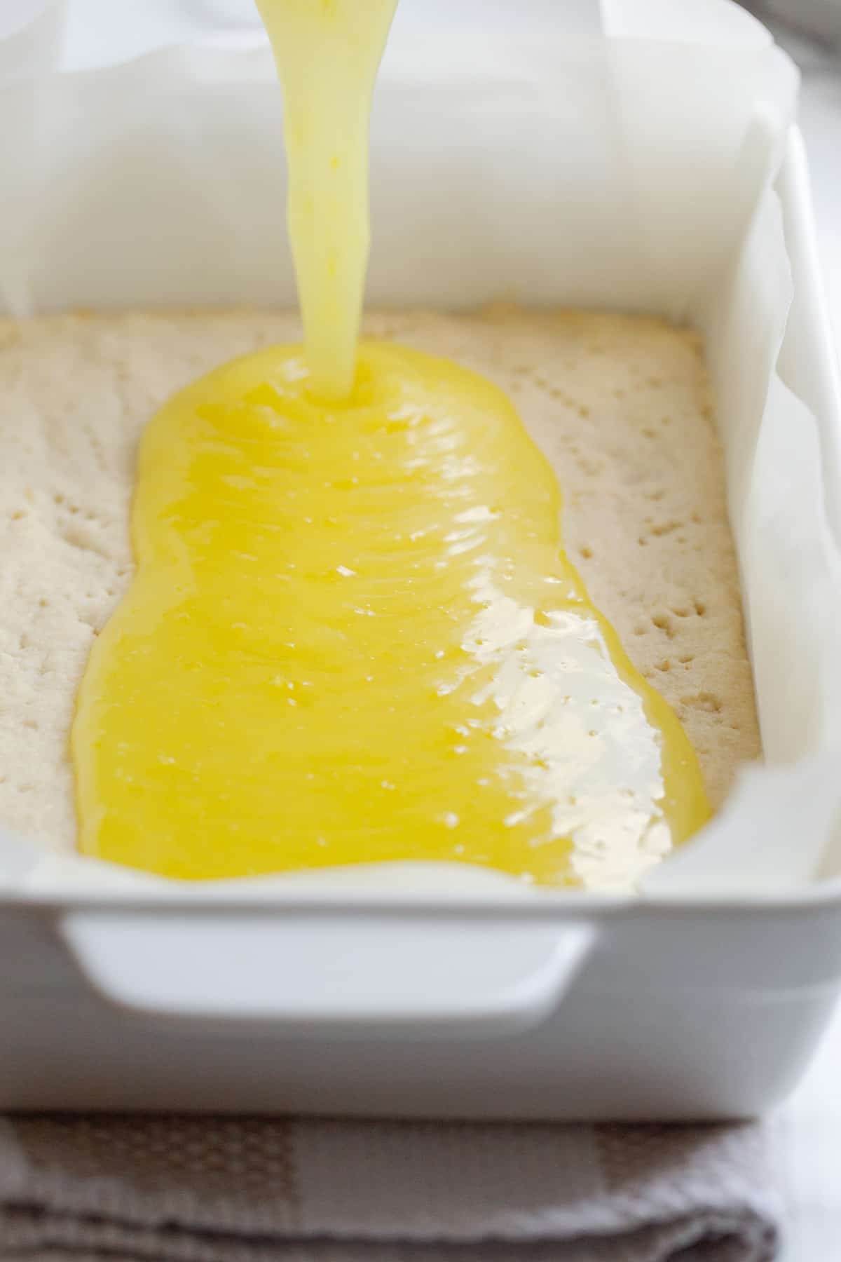Pouring the lemon layer over the vegan shortbread crust.