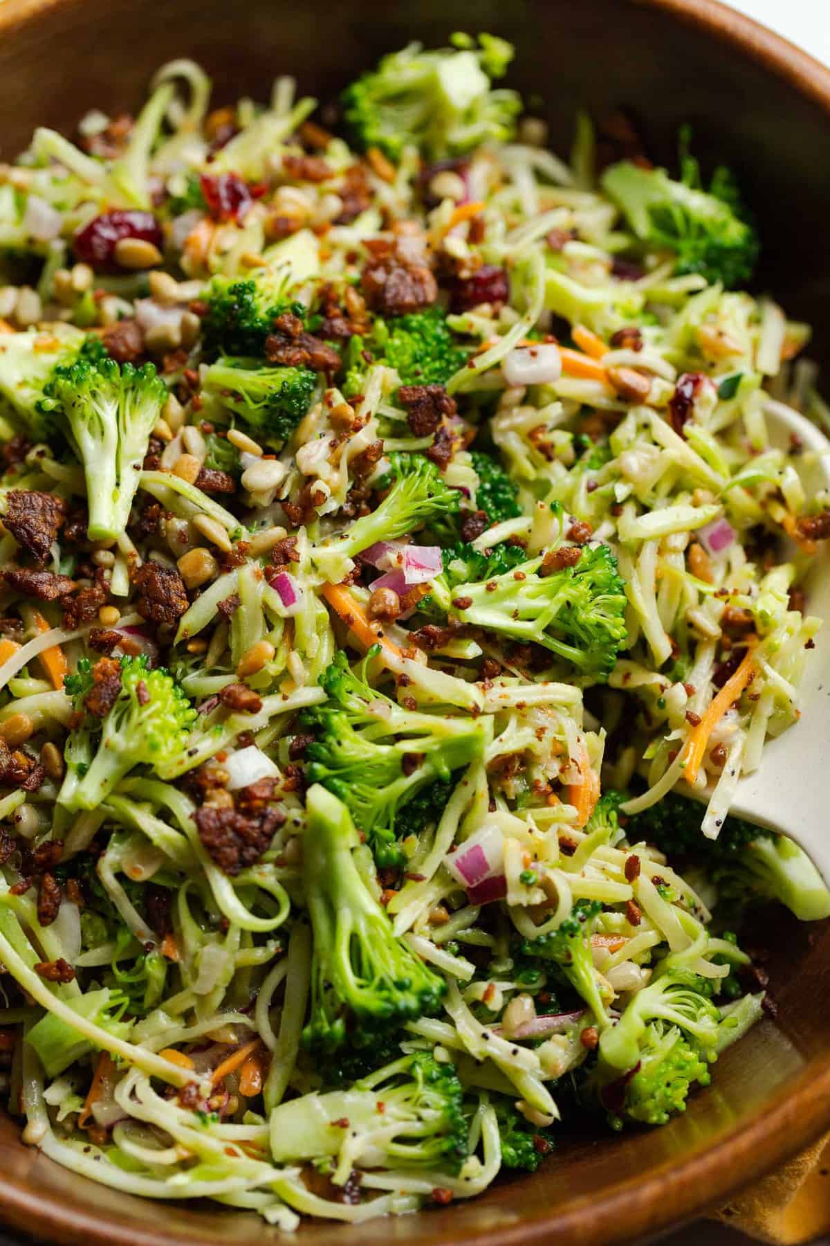 Close up of a wooden serving bowl full of vegan broccoli slaw salad.