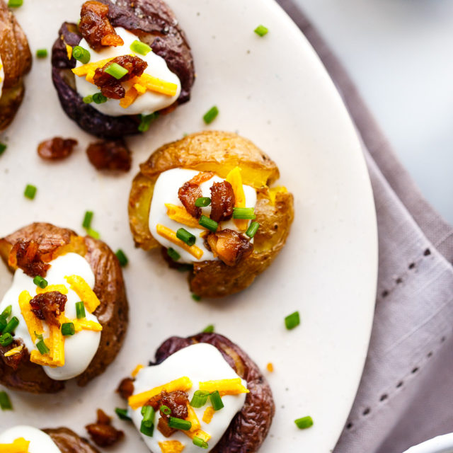 Smashed potatoes loaded with vegan sour cream, vegan cheese, tempeh bacon and chives.