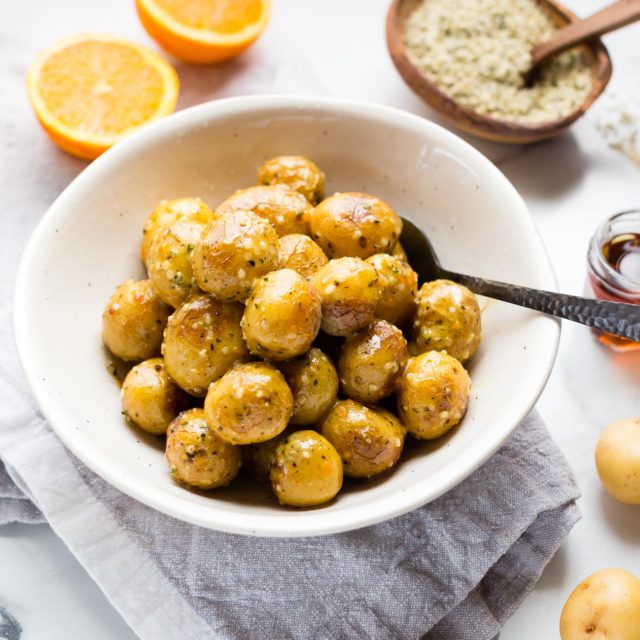 A bowl of vegan orange dijon little potatoes on a marble counter top.