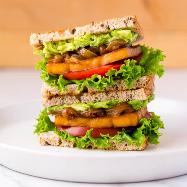 Stacked smoky maple tofu sandwiches on a plate.