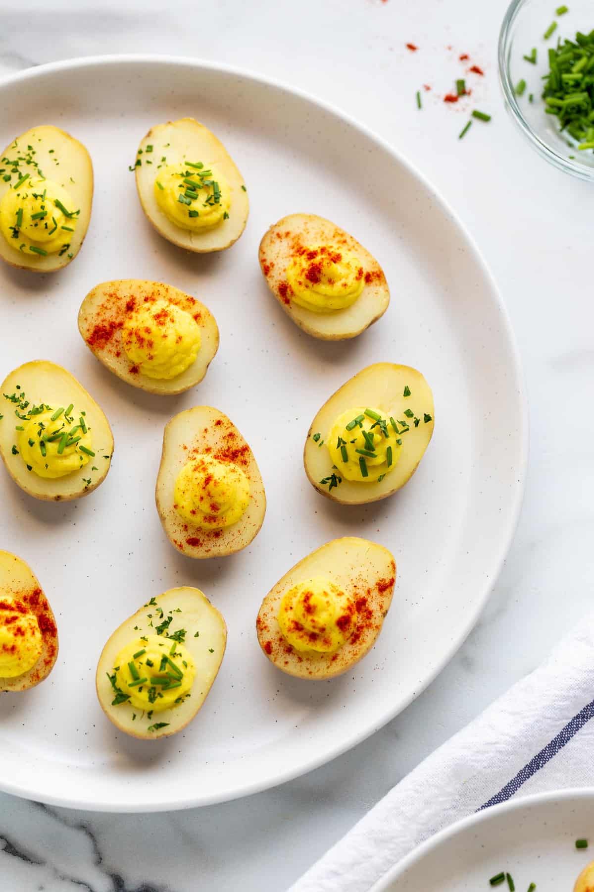 veganské ďábelské vaječné brambory zdobené paprikou a čerstvou pažitkou.